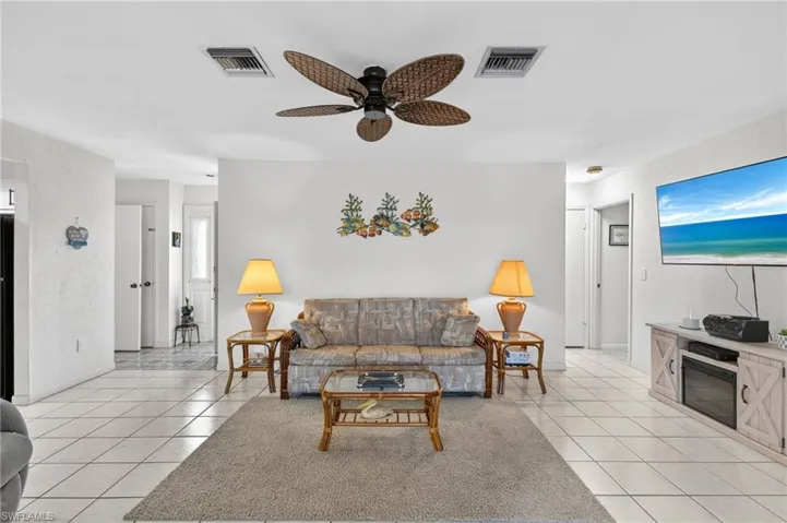 Expansive living area featuring large format tile flooring and a ceiling fan with rattan-style blades