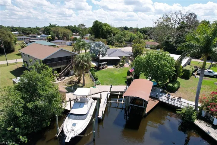 Dock area featuring boat lift, a water view, a yard, and a patio area