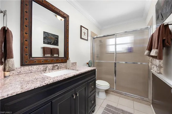 Full bath featuring ornamental molding, vanity, a stall shower, and light tile patterned floors
