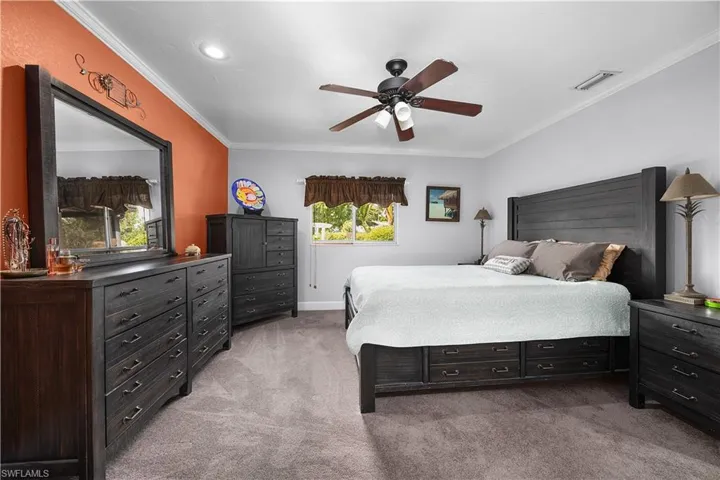 Bedroom featuring light colored carpet, a ceiling fan, and crown molding