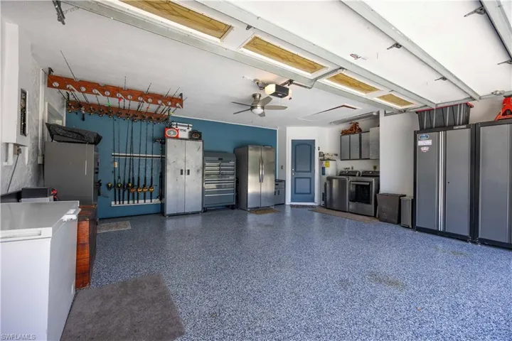 Garage featuring freestanding refrigerator, a ceiling fan, washer and clothes dryer, electric panel, and electric water heater