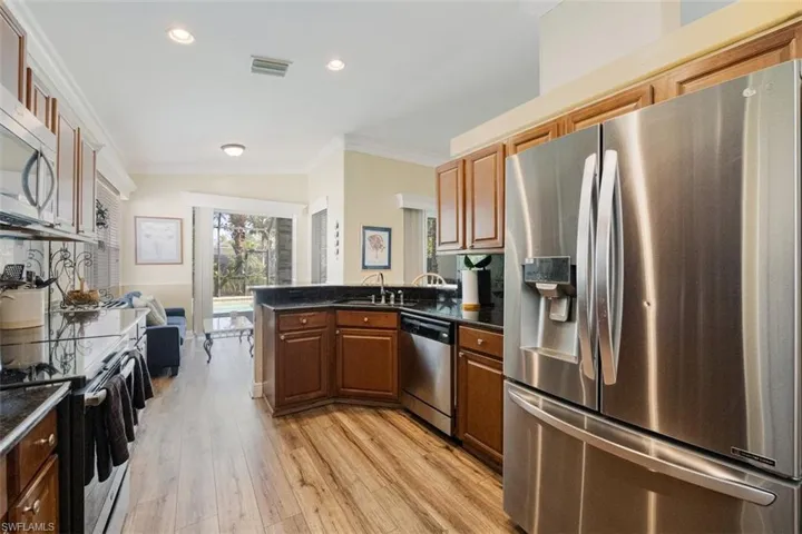 Kitchen featuring  dark countertops, crown molding, and appliances with stainless steel finishes