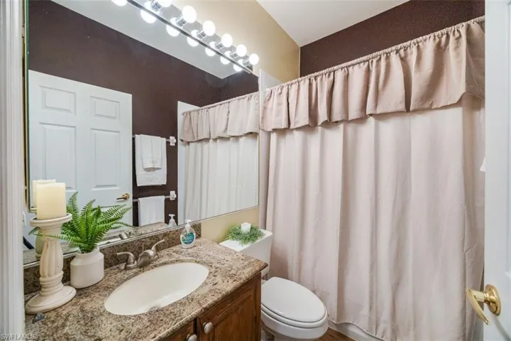 Bathroom with toilet, vanity, and curtained shower