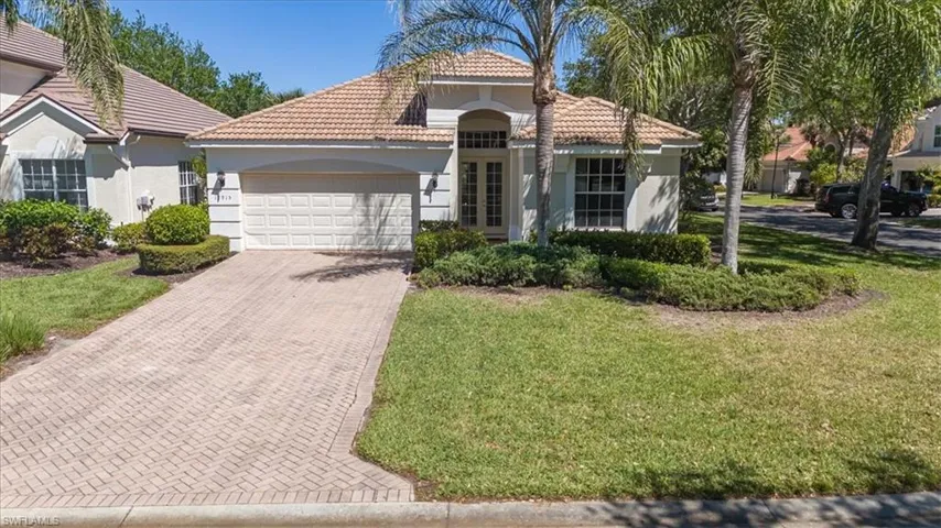 Mediterranean / spanish house with a tiled roof, decorative driveway, an attached garage, a front yard, and stucco siding