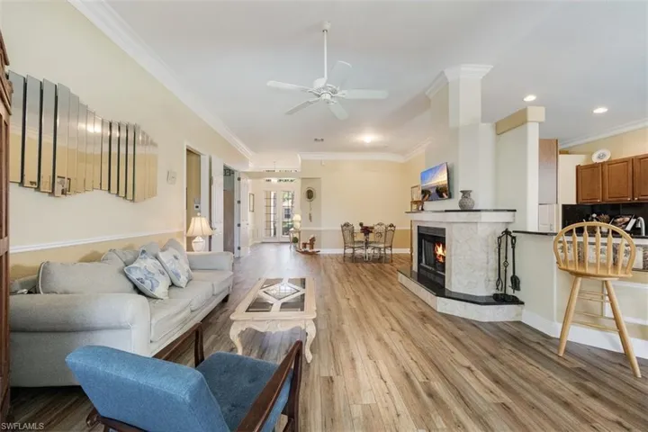 Living area with baseboards, crown molding, light wood-style floors, and ceiling fan