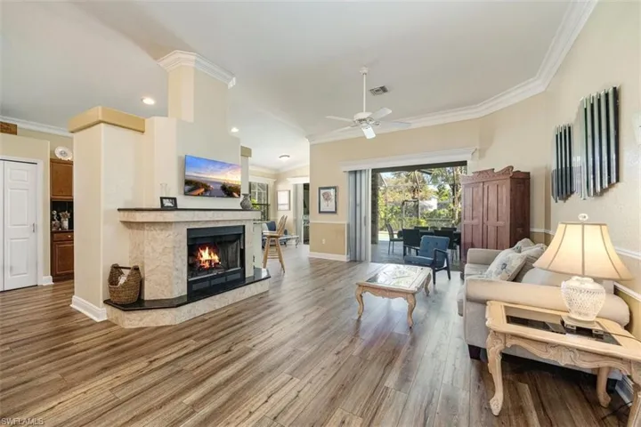 Living area with a ceiling fan, crown molding, wood finished floors, and a premium fireplace