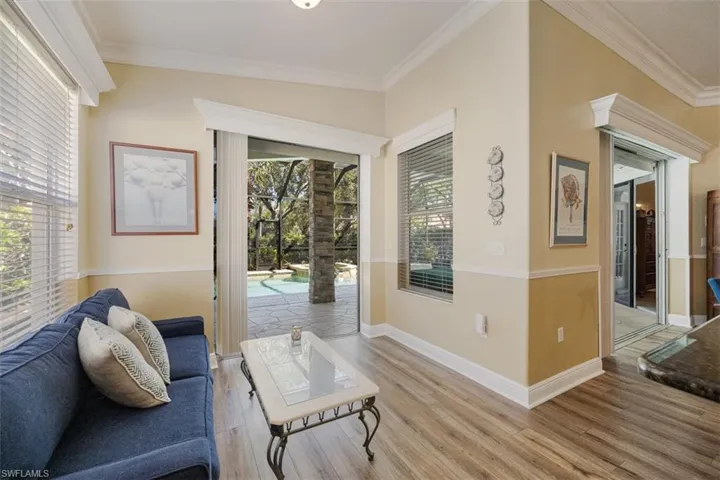 Living area with plenty of natural light, crown molding, and light wood-style floors