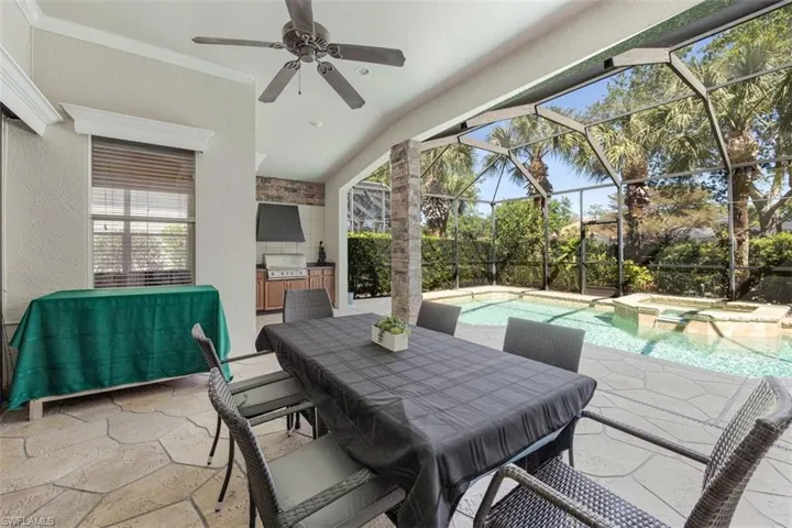 View of patio / terrace with glass enclosure, a pool with connected hot tub, area for grilling, outdoor dining space, and ceiling fan