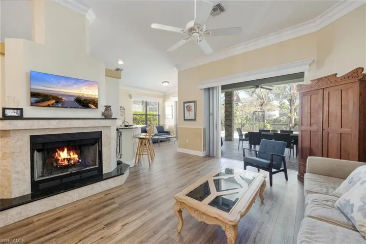 Living room featuring a premium fireplace, ornamental molding,  a ceiling fan, and wood finished floors