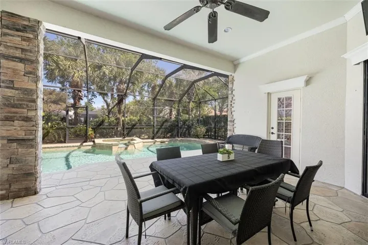 View of patio featuring ceiling fan, outdoor dining space, a pool with connected hot tub, and a lanai