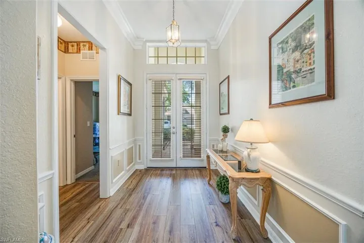 Doorway with french doors, a wainscoted wall, ornamental molding
