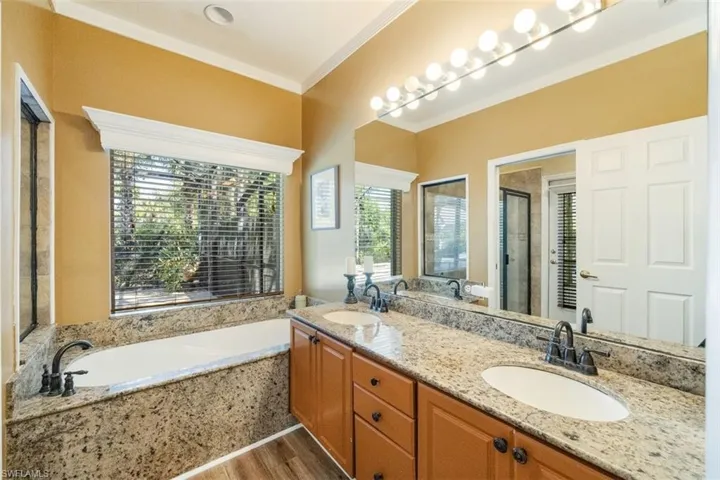 Bathroom with a bath, ornamental molding, a sink, and a shower stall