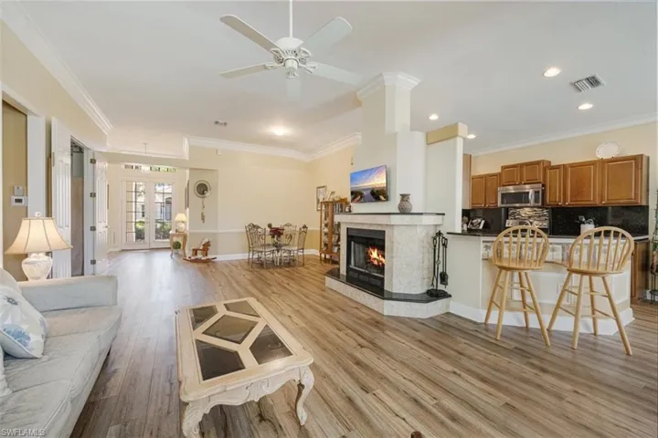 Living area featuring light wood-style flooring, crown molding, baseboards, and a ceiling fan