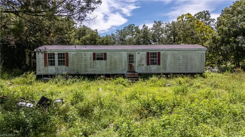 Back of house featuring view of wooded area and entry steps