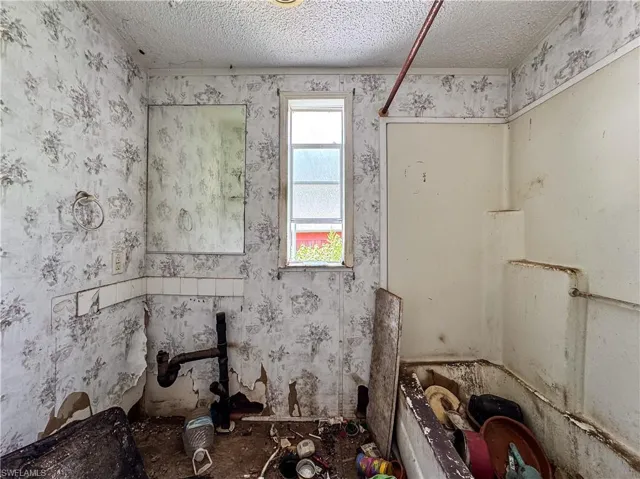 Full bathroom featuring wallpapered walls, a textured ceiling, and a bath