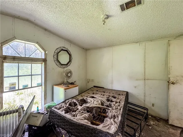 Bedroom featuring vaulted ceiling and a textured ceiling