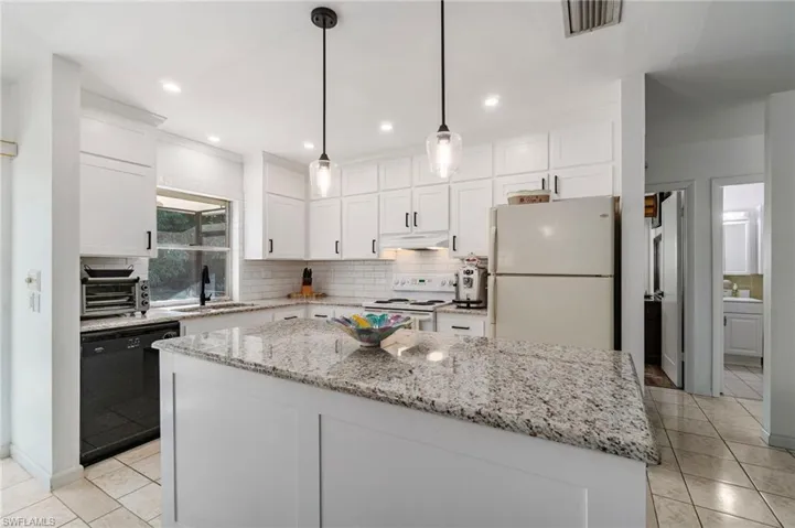 Kitchen featuring white appliances, light tile patterned flooring, a kitchen island, backsplash, and recessed lighting