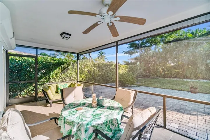 Sunroom / solarium with expansive windows, ceiling fan, tile patterned floors, a wall mounted air conditioner, and outdoor dining area