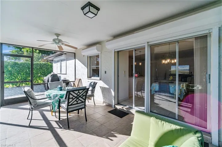 Sunroom with a wall of windows, ceiling fan, tile patterned flooring, outdoor dining area, and a wall unit AC