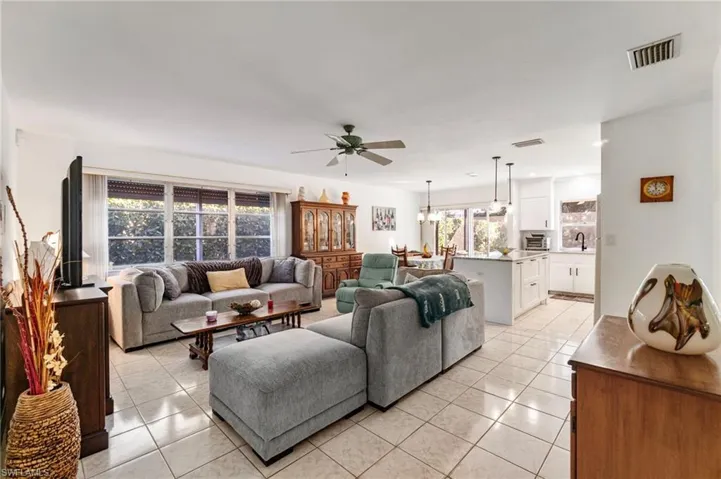 Living area featuring light tile patterned floors, ceiling fan, and a chandelier