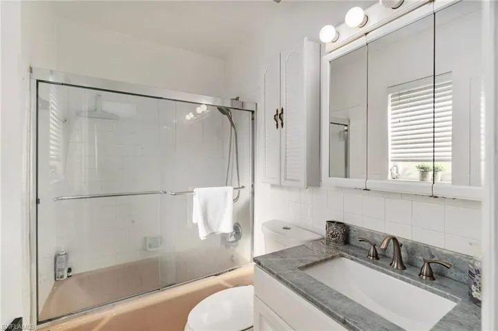 Bathroom with vanity, decorative backsplash, and enclosed tub / shower combo