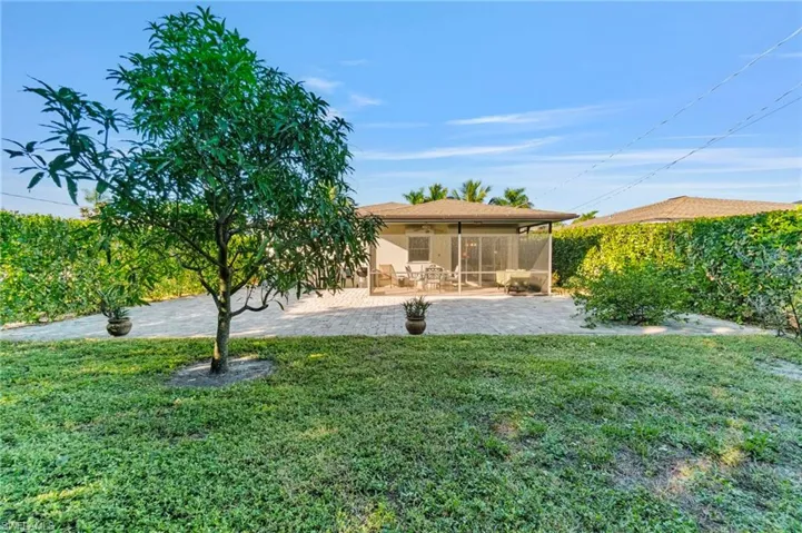 Rear view of property featuring a lawn, a patio area, and a sunroom
