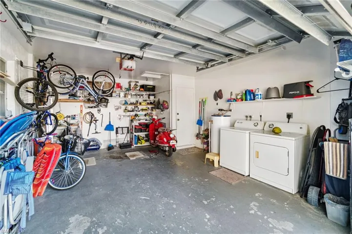 Garage featuring independent washer and dryer, a workshop area, water heater, and a garage door opener