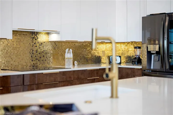 Interior details with tasteful backsplash, refrigerator with ice dispenser, white cabinetry, and modern cabinets