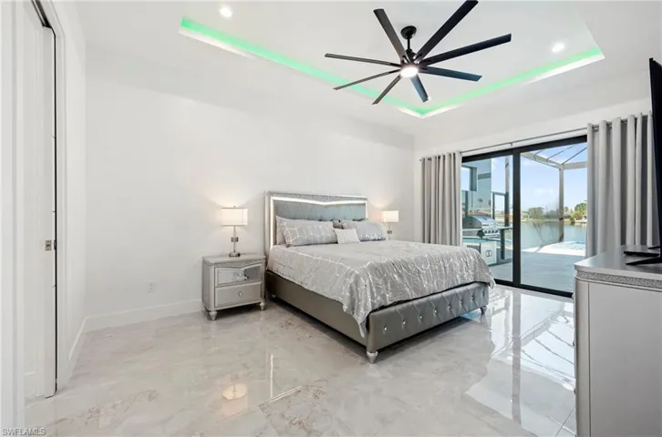 Bedroom featuring a raised ceiling, recessed lighting, access to exterior, and baseboards