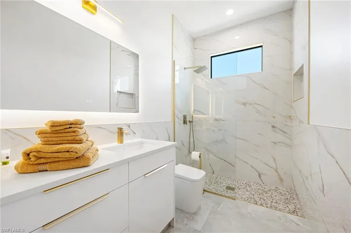 Full bath featuring a marble finish shower, toilet, recessed lighting, marble finish floor, and vanity