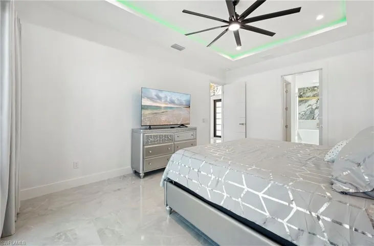 Bedroom featuring a ceiling fan, visible vents, baseboards, a tray ceiling, and recessed lighting