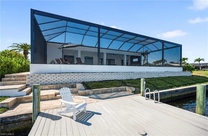 View of dock with a lanai, a yard, and a water view