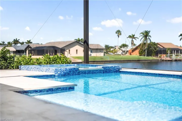 View of swimming pool with a water view, a residential view, and a pool with connected hot tub