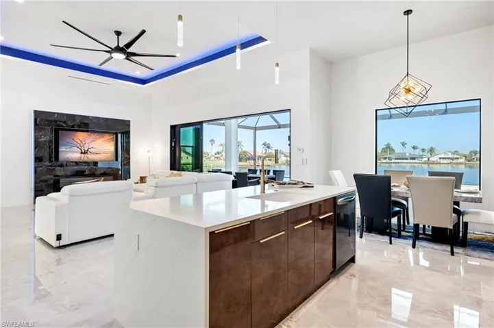 Kitchen with marble finish floor, modern cabinets, a tray ceiling, dark brown cabinets, and ceiling fan