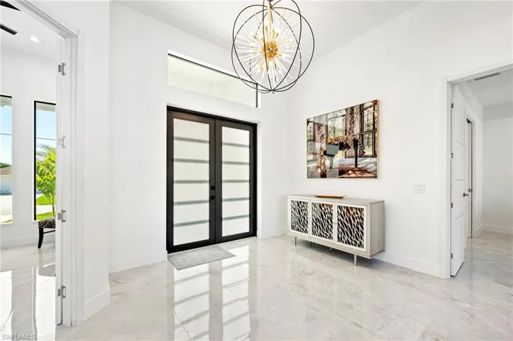 Entrance foyer featuring visible vents, marble finish floor, baseboards, and an inviting chandelier