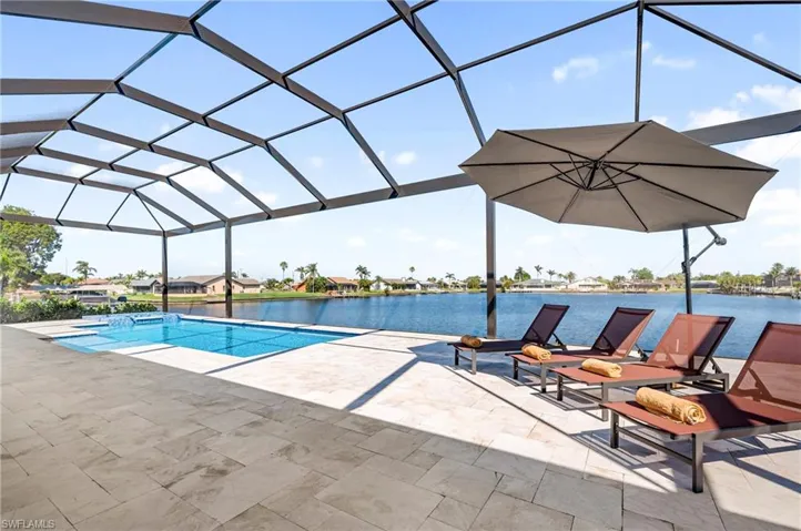 Outdoor pool with glass enclosure, a patio area, and a water view