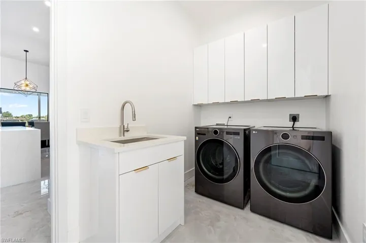 Laundry room featuring washer and clothes dryer, cabinet space, and a sink