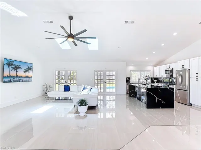 Living room with lofted ceiling, french doors, recessed lighting, a skylight, and light tile patterned floors