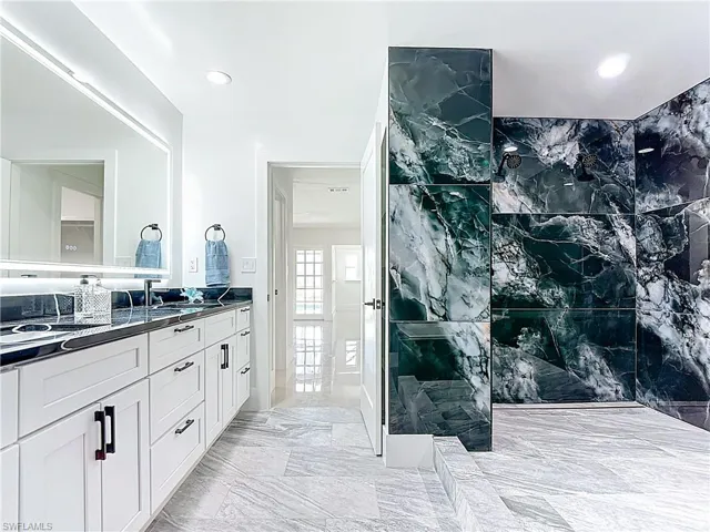 Bathroom featuring double vanity, marble finish floors, a walk in shower, and recessed lighting