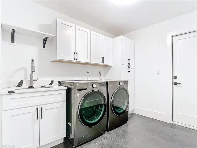 Laundry room featuring independent washer and dryer, cabinet space, and tile patterned flooring