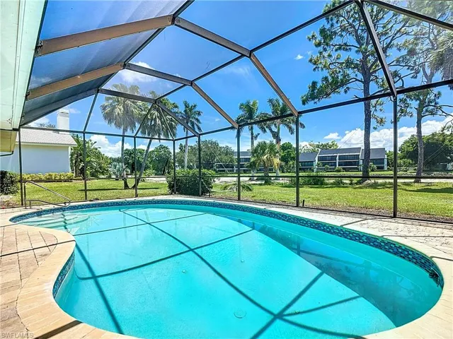 Outdoor pool with a yard, a patio area, and glass enclosure