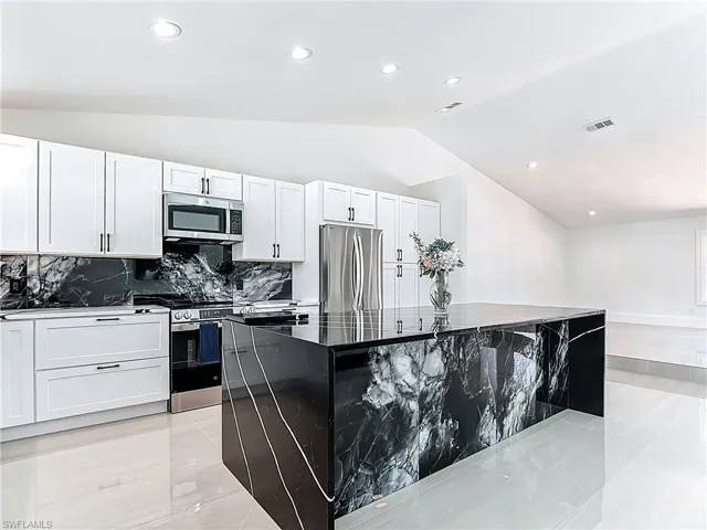 Kitchen featuring lofted ceiling, tasteful backsplash, recessed lighting, a center island, and stainless steel appliances