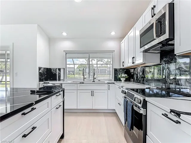 Kitchen featuring stainless steel appliances, backsplash, recessed lighting, and white cabinets