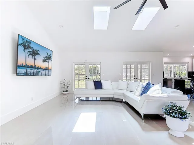 Living room with french doors, vaulted ceiling, a skylight, and recessed lighting