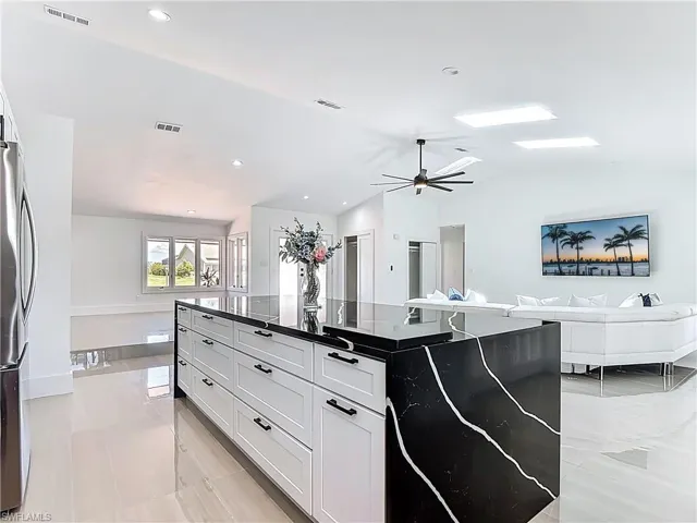 Kitchen with vaulted ceiling, open floor plan, freestanding refrigerator, dark countertops, and a ceiling fan