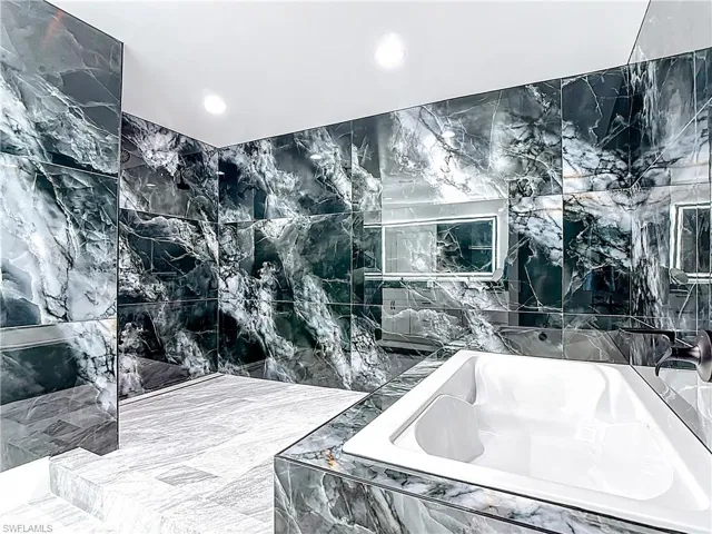 Full bathroom featuring tile walls, a garden tub, and recessed lighting