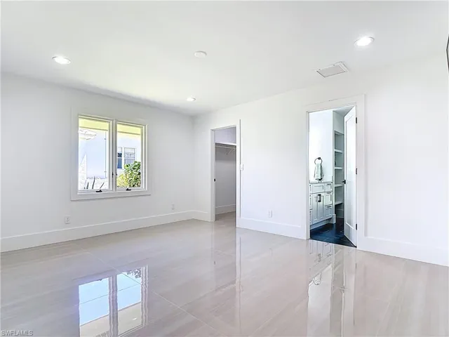 Unfurnished bedroom with recessed lighting, a spacious closet, and ensuite bath