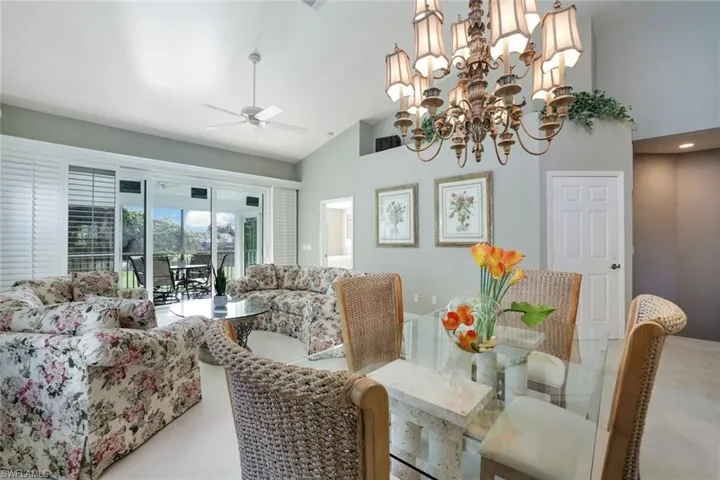 Dining space featuring ceiling fan with notable chandelier, carpet floors, and high vaulted ceiling