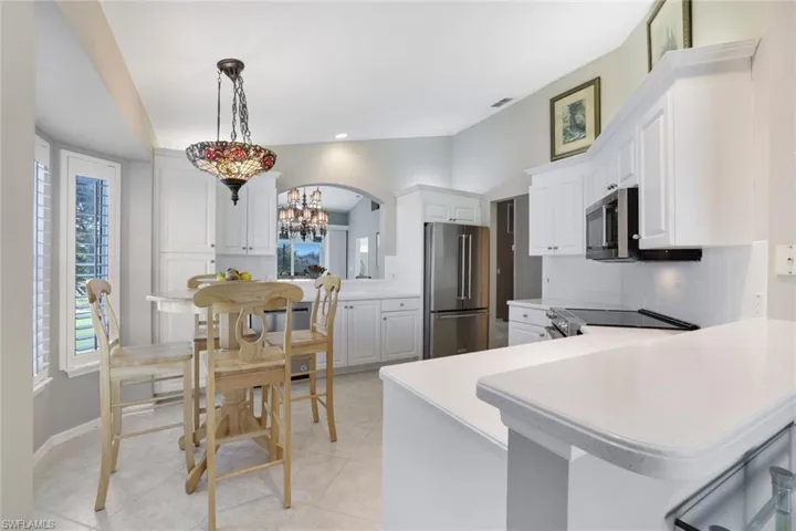 Kitchen with pendant lighting, white cabinets, light tile patterned floors, appliances with stainless steel finishes, and kitchen peninsula