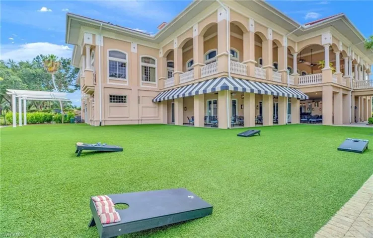 Back of property featuring a pergola, a balcony, and a yard